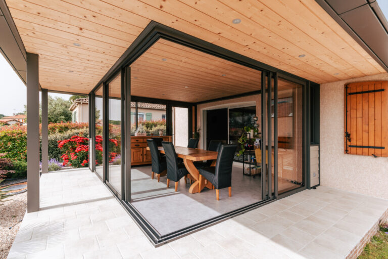 Extension aluminium Metzger en façade avec toiture bois et jardin paysager