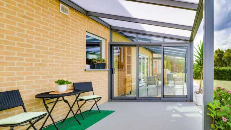 Véranda Metzger avec pergola intégrée en aluminium gris sur terrasse de maison moderne