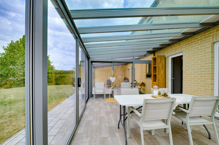 Salle à manger installée dans une véranda Metzger avec grandes baies vitrées